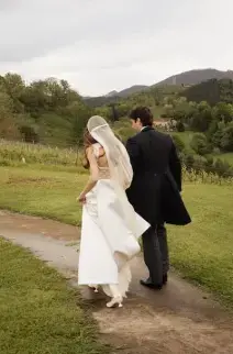 Novia y novio caminando por un sendero natural.